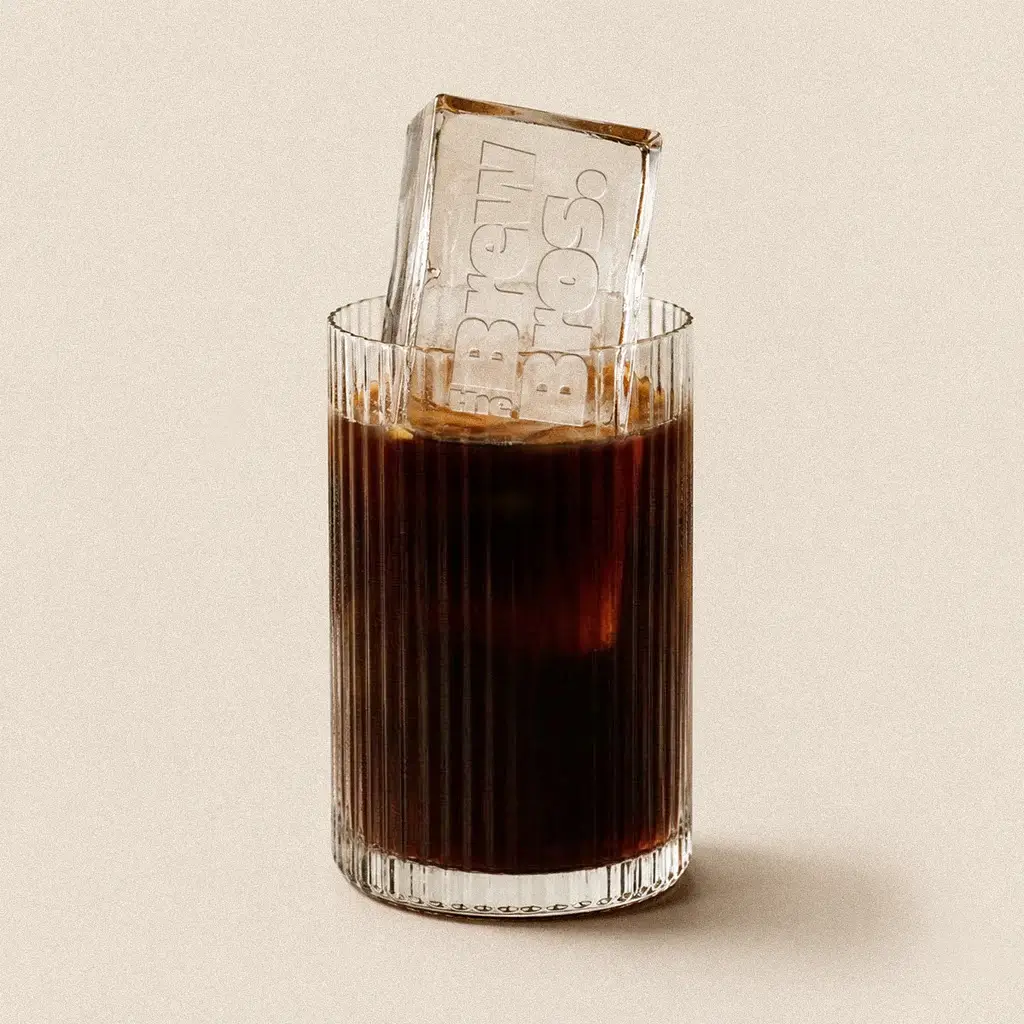 Ryflowana szklanka z kawą cold brew i dużą przezroczystą kostką lodu z logo The Brew Bros